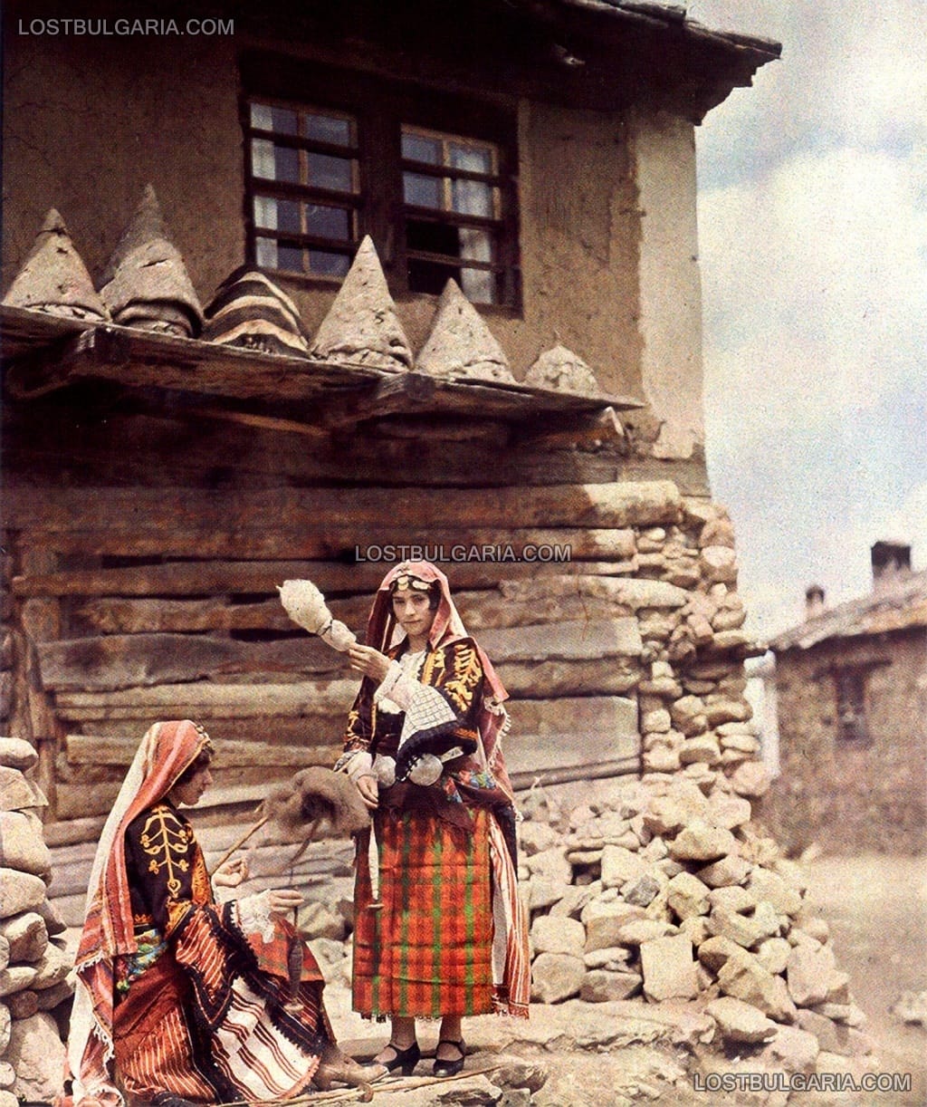 Момичета в родопски носии пресукват вълна с хурки, над тях - глинени, конични кошери, 1932 г.