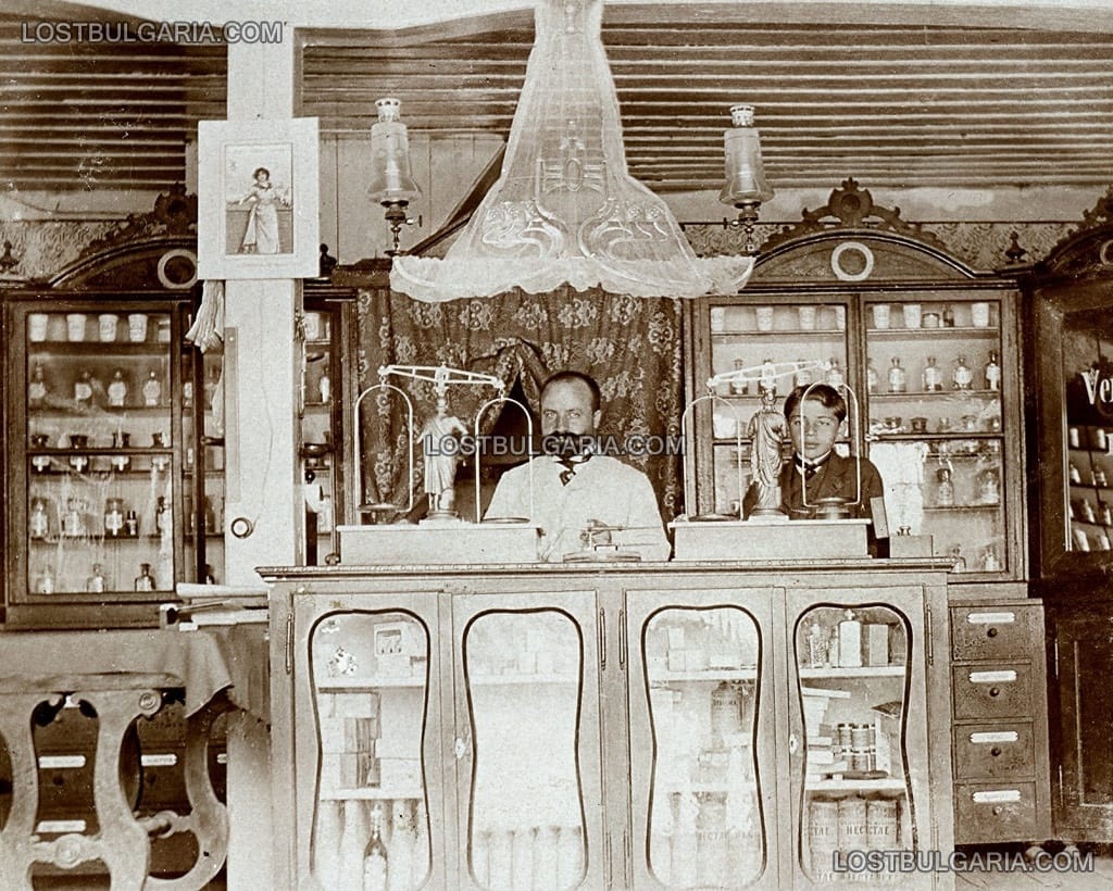 Аптекар в своята аптека с помощника си, началото на ХХ век