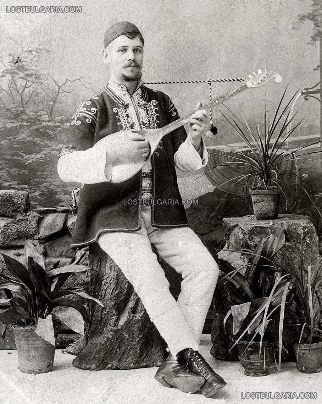 Млад мъж, облечен в носия от Шопско свири на мандолина, около 1900 г.