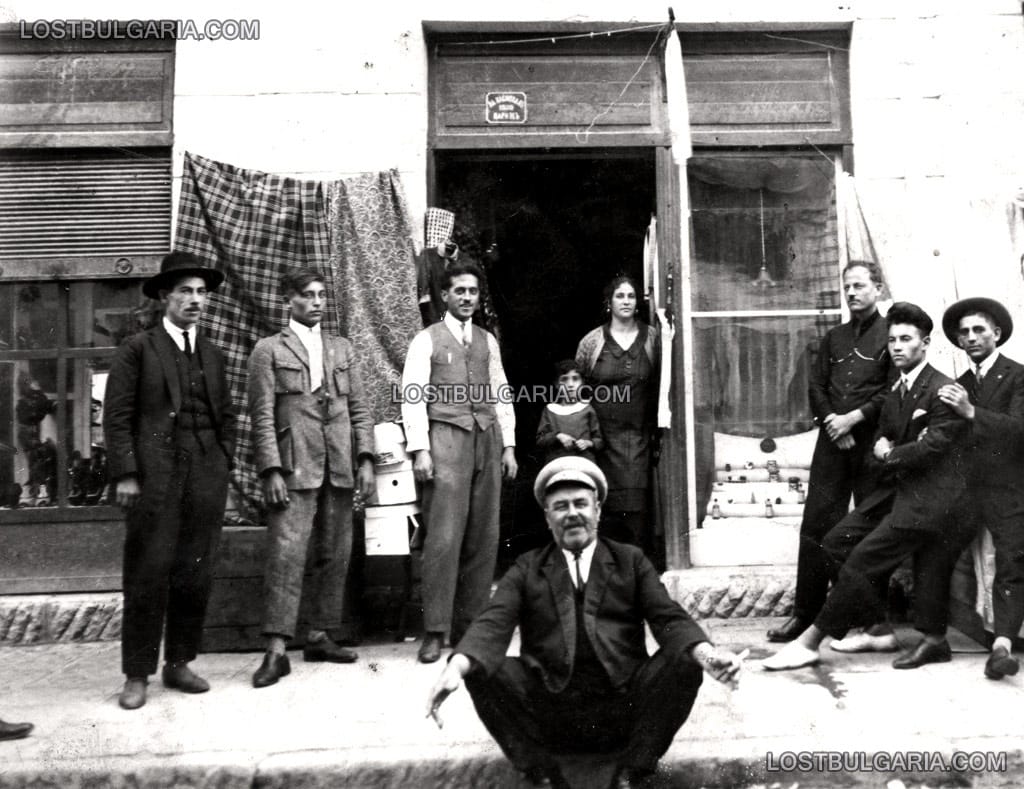 Група хора пред магазини за обувки, платове и дрехи, неизвестно къде, 1927 г.