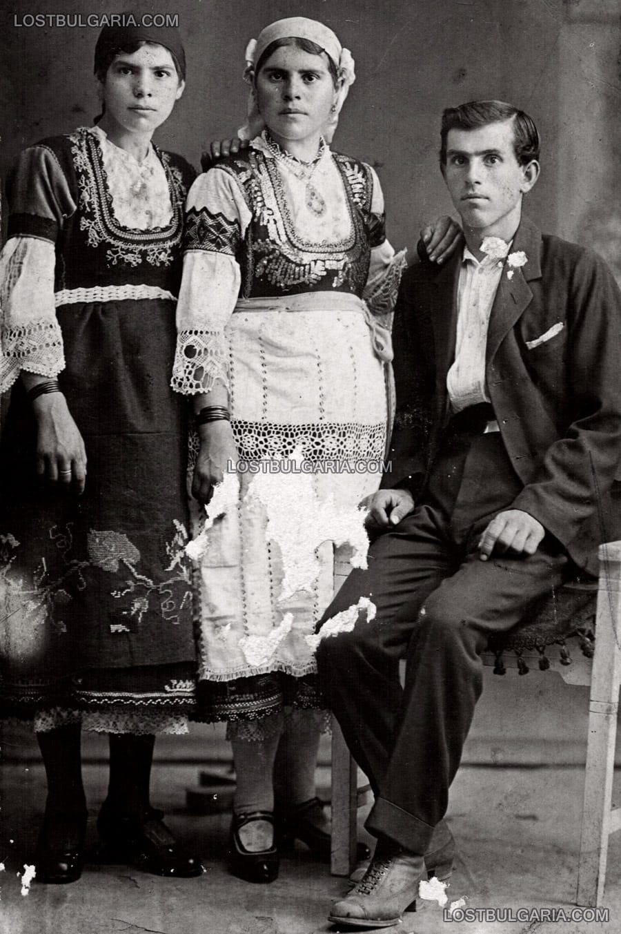 Млади момичета, облечени в носии и млад мъж в градско облекло, вероятно годежна снимка, село Варвара, 1923 г.