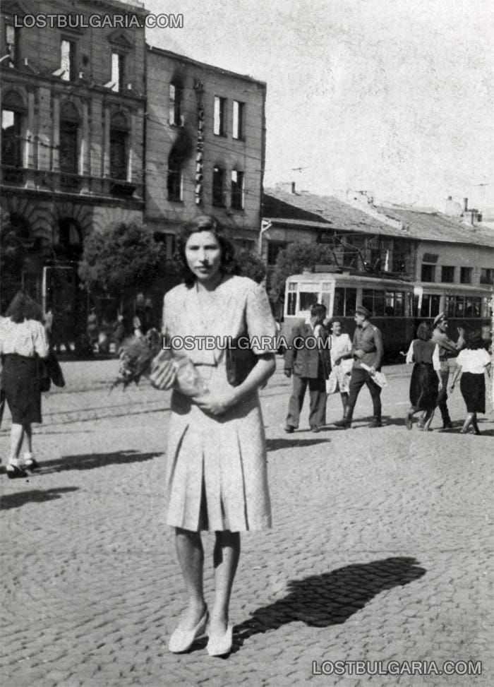 София, млада жена пред изгорялата фасада на колбасарница "Докузанов" на бул. "Дондуков", след бомбардировките. Лятото на 1944 г.