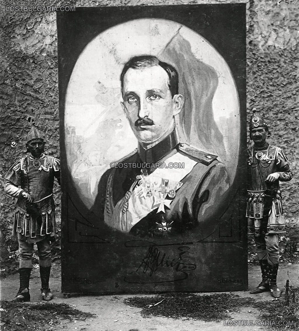 Двама мъже, облечени в театрални костюми, държат портрет на Цар Борис III, подписан Н. Вълчев, 1920 г. - неизвестно къде и по какъв повод, вероятно 20-те години на ХХ век