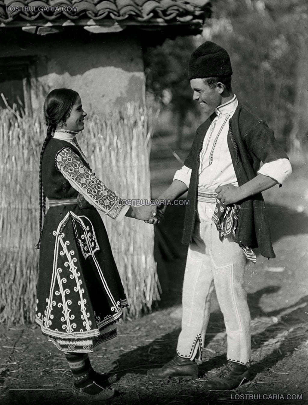 Млада жена и млад мъж, облечени в носии от Софийско, аранжирана фотография, озаглавена "Среща", 20-те години на ХХ век