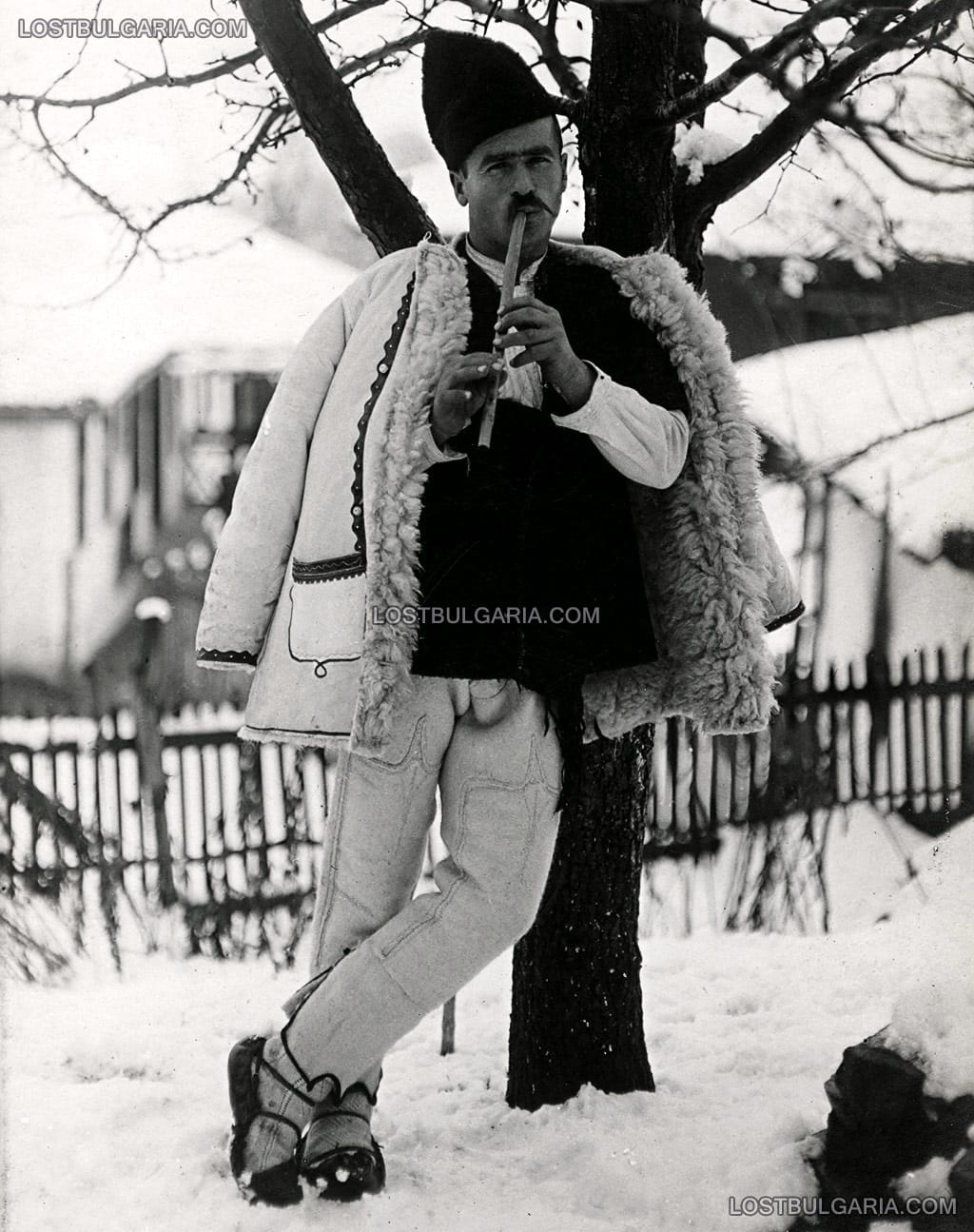 Млад селянин от Софийско, облечен в зимна шопска носия от овча кожа свири на дудук, 30-те години на ХХ век
