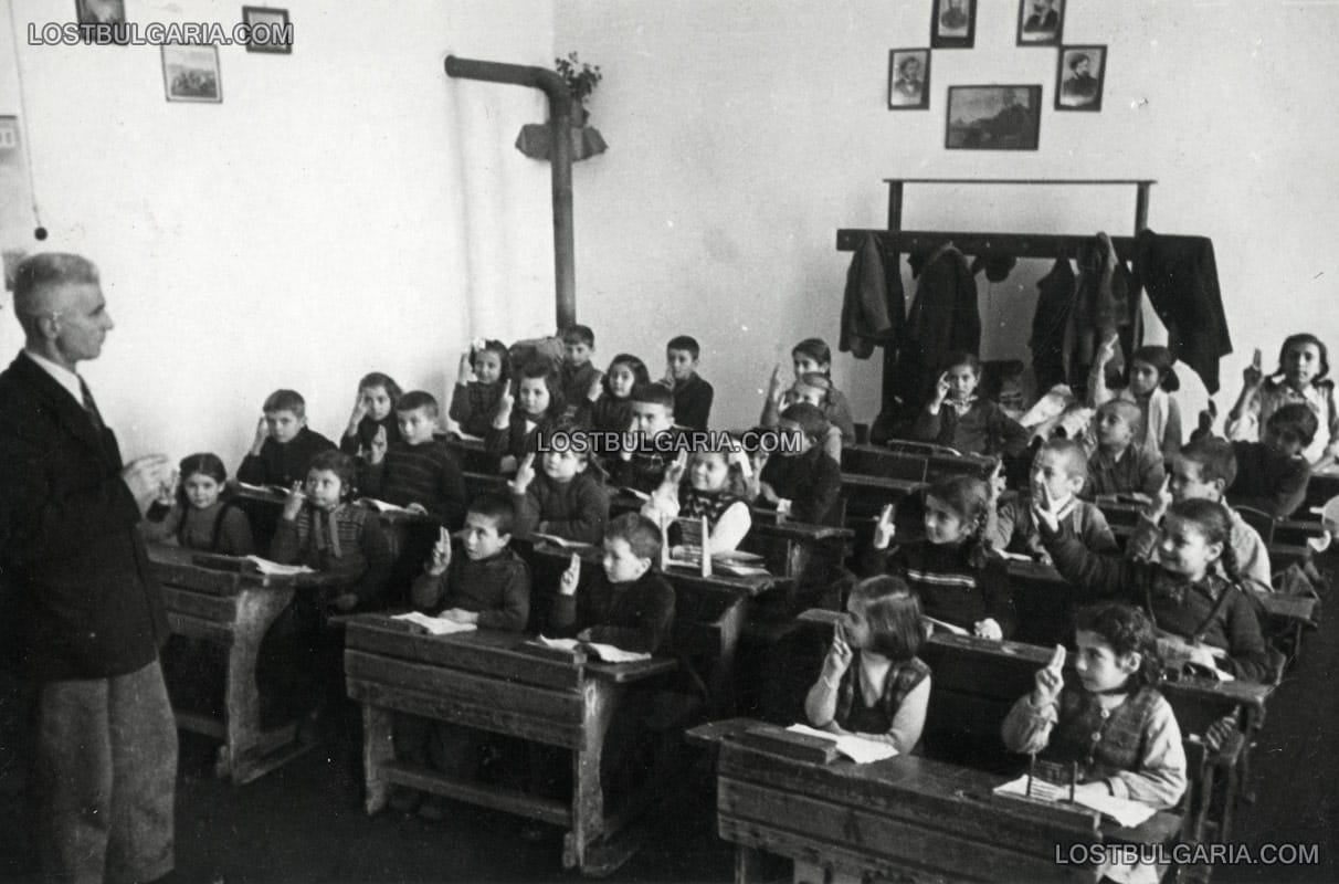 Ученици от началните класове на селско училище, вдигнали ръце за правилен отговор, неизвестно къде, края на 40-те години на ХХ век